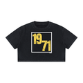 A black cropped t-shirt featuring a distressed yellow '1971' graphic inside a white square frame on the front, displayed flat against a solid white background.