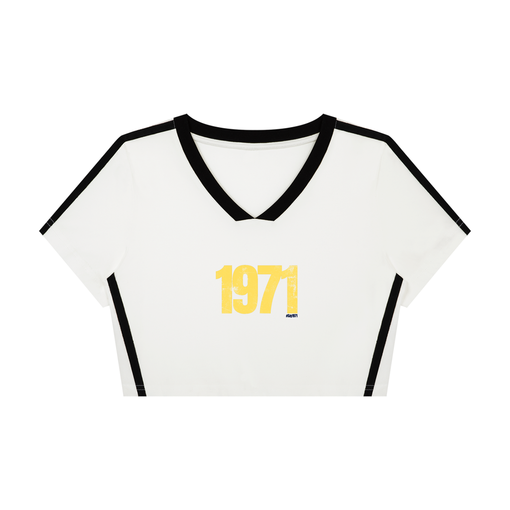 A white short-sleeve crop top with black trim on the V-neck collar, sleeve edges, and sides, featuring a yellow distressed '1971' graphic on the chest.